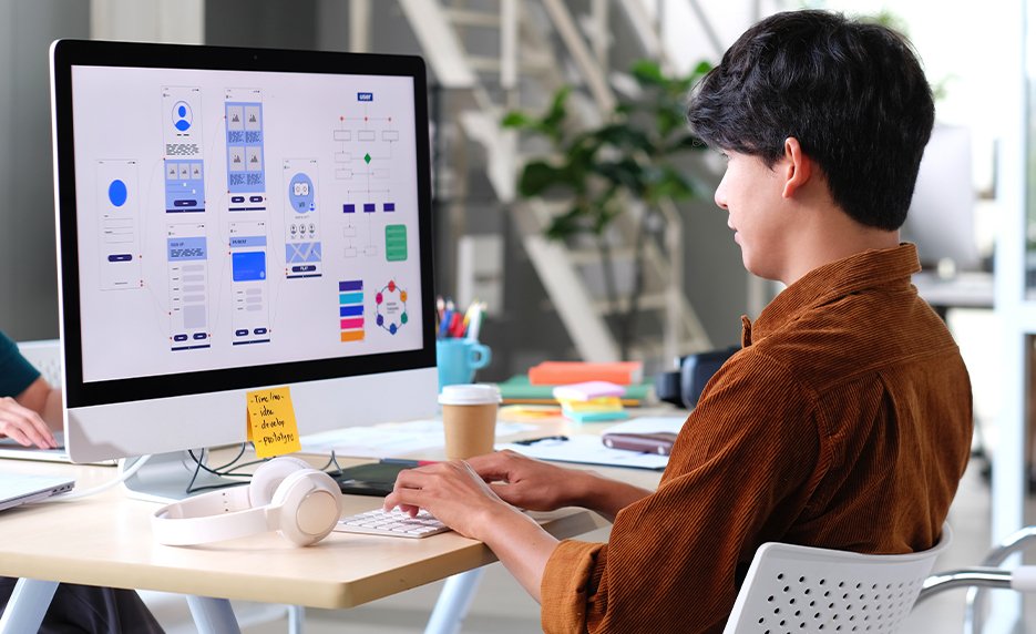 A web design professional working on a laptop with code and design tools visible on the screen.